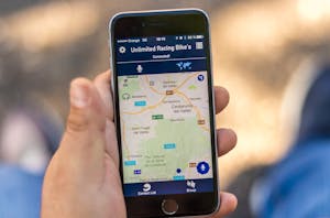 Hand holding smartphone displaying a GPS map application with location data.